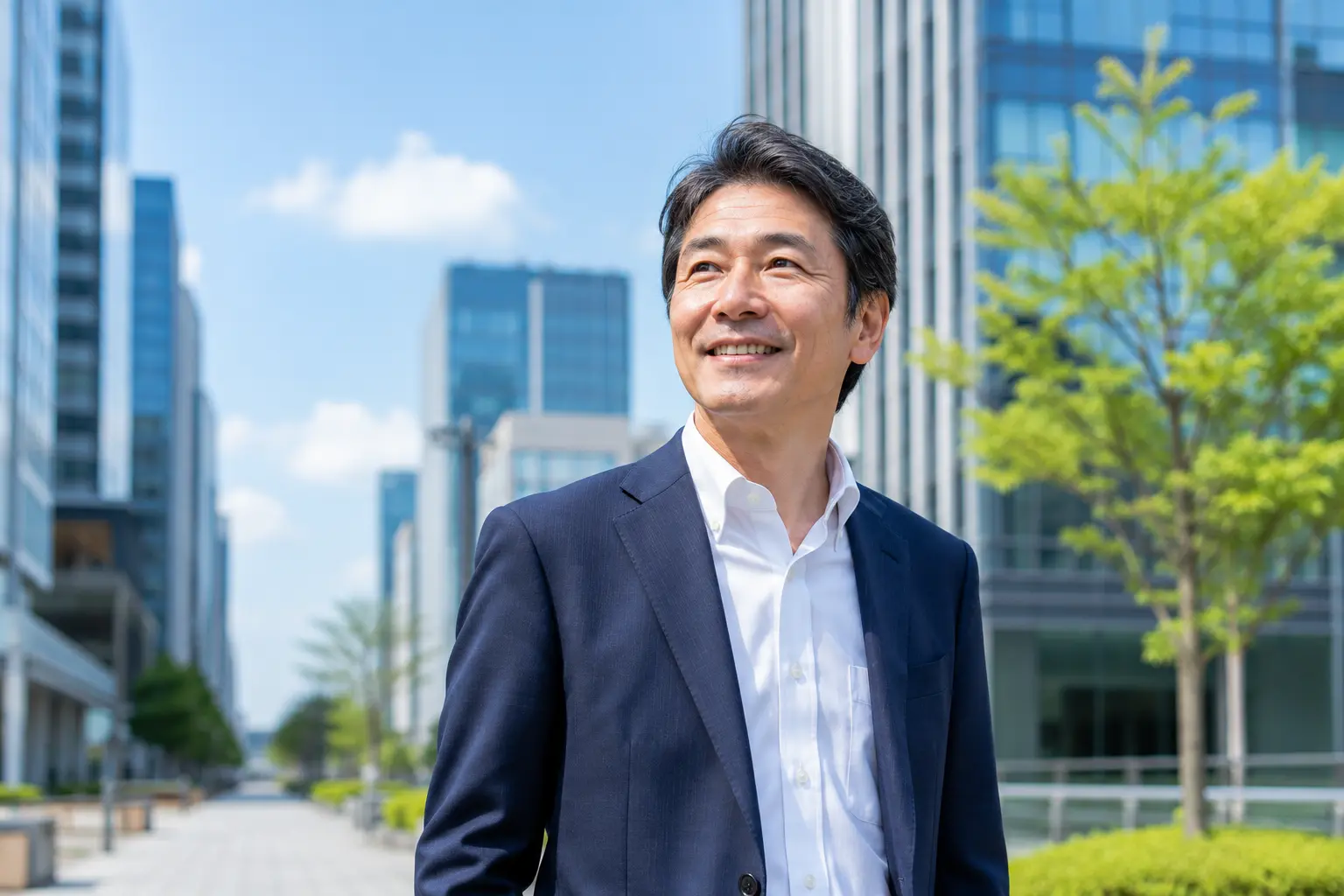 青空のオフィス街で安心した爽やかな笑顔を見せる50代の男性ビジネスマン