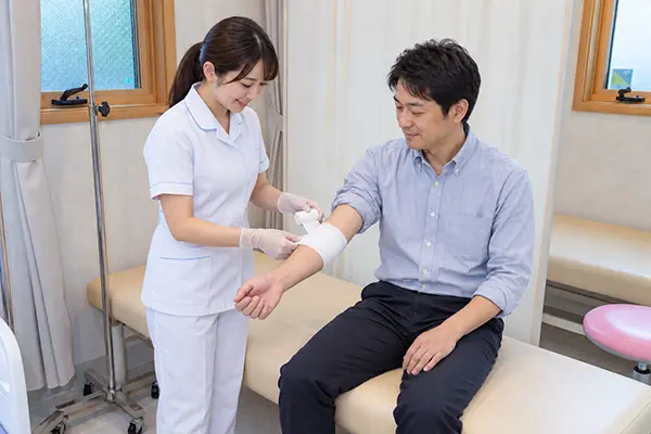 男性患者の腕に包帯を巻く女性看護師